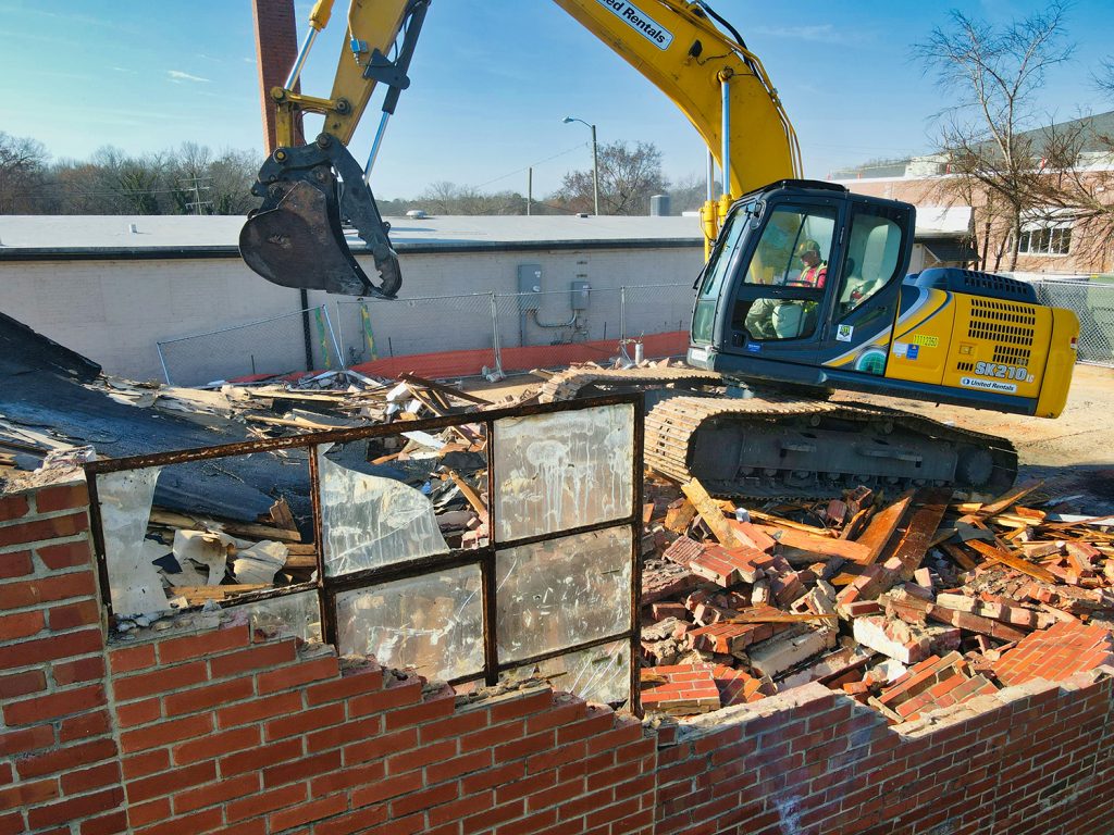 Une pelleteuse détruit un bâtiment en briques